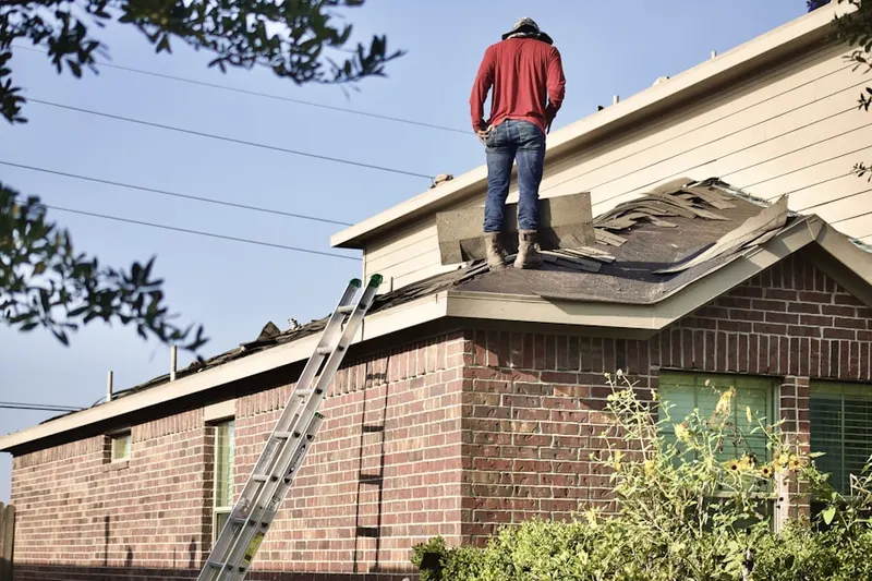 Professional roofer working on a residential roof in Landen